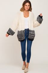woman wearing cream and black colorblock chunky knit cardigan with blue skinny jeans and tan mules