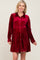 blonde woman wearing a burgundy velvet long sleeve button down maternity dress