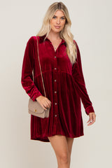 woman wearing a long sleeve burgundy velvet button down mini dress with a tan quilted crossbody bag