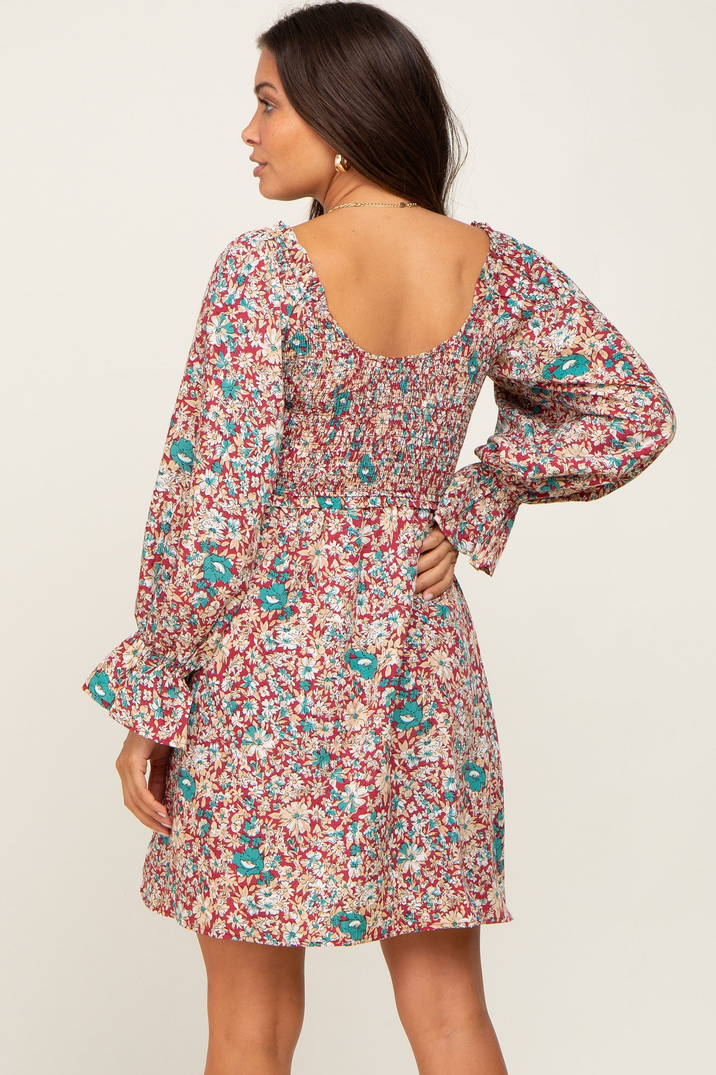 woman wearing a long sleeve floral mini dress with a smocked back and scoop neckline