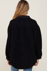 Back view of a woman wearing a black oversized sherpa fleece jacket with a collar and ribbed cuffs