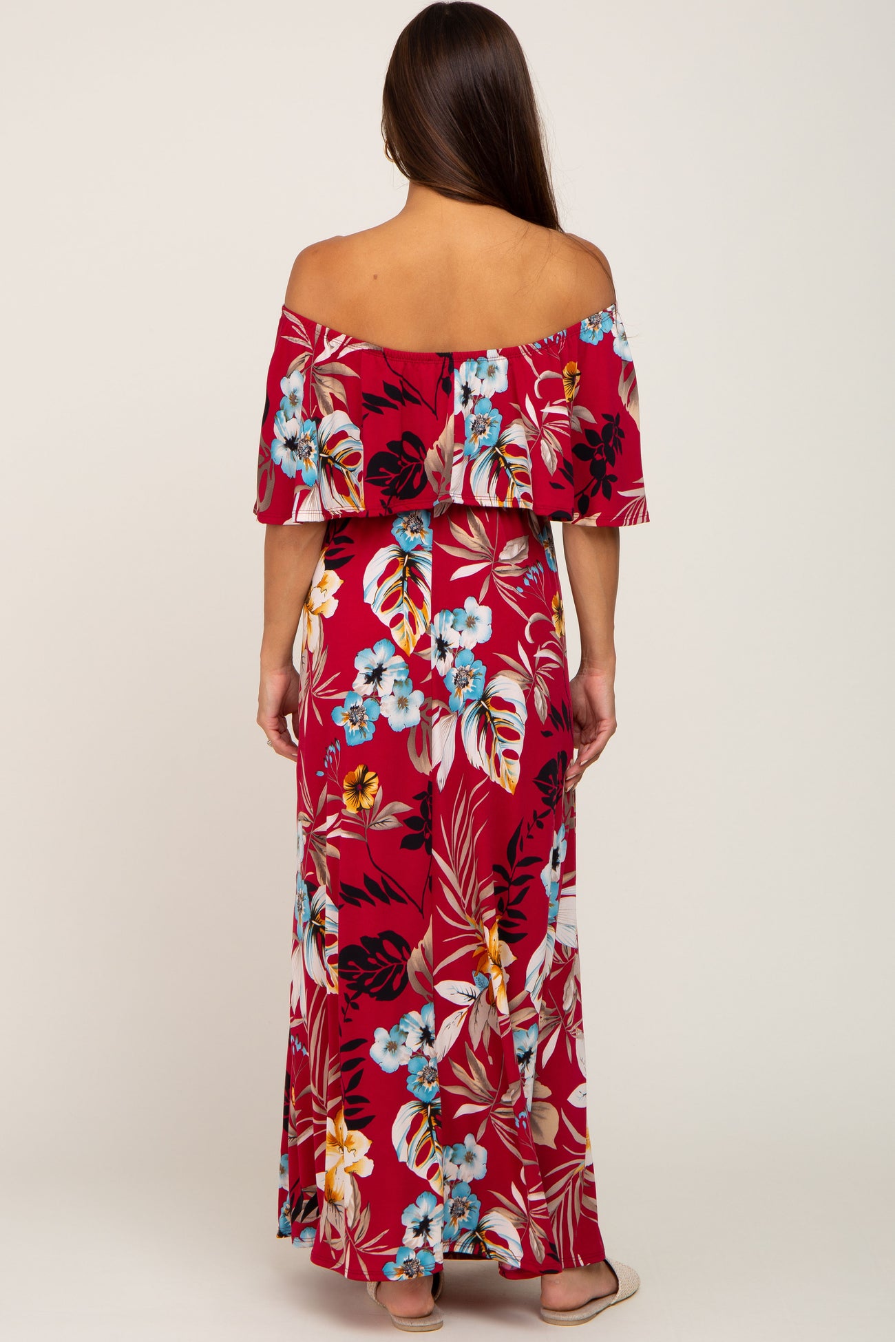 woman wearing a red floral off-the-shoulder maternity maxi dress with a flowing fit