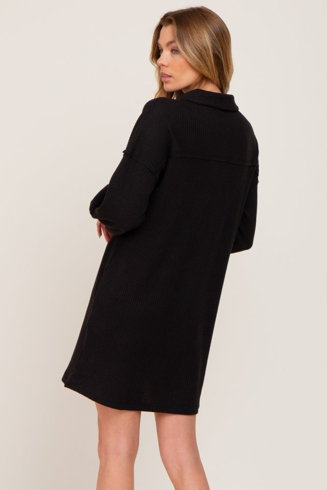 Woman wearing a black long sleeve waffle knit mini dress with a collar seen from the back