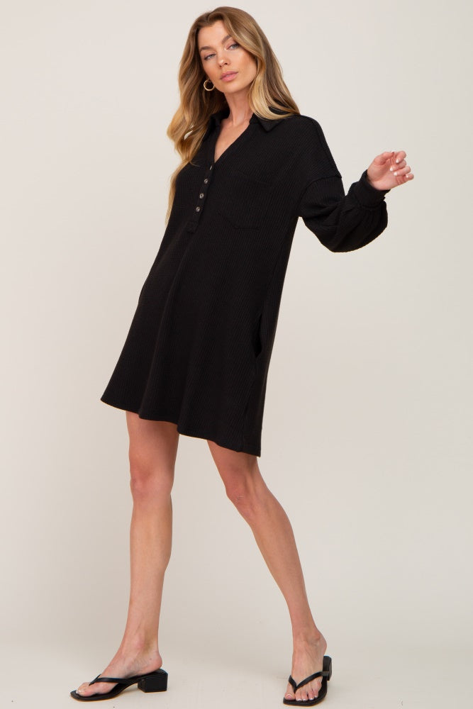 woman wearing a black long sleeve waffle knit henley mini dress with black sandals