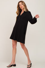 woman wearing a black long sleeve waffle knit henley mini dress with black sandals