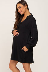 pregnant woman wearing a black long sleeve waffle knit maternity dress with buttons and pockets