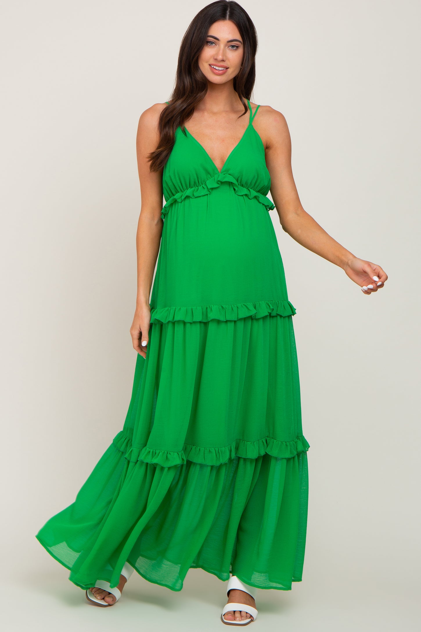woman wearing a green tiered maternity maxi dress with ruffle details and spaghetti straps