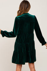 back view of woman wearing a dark green velvet tiered mini dress with long sleeves and ruffled cuffs