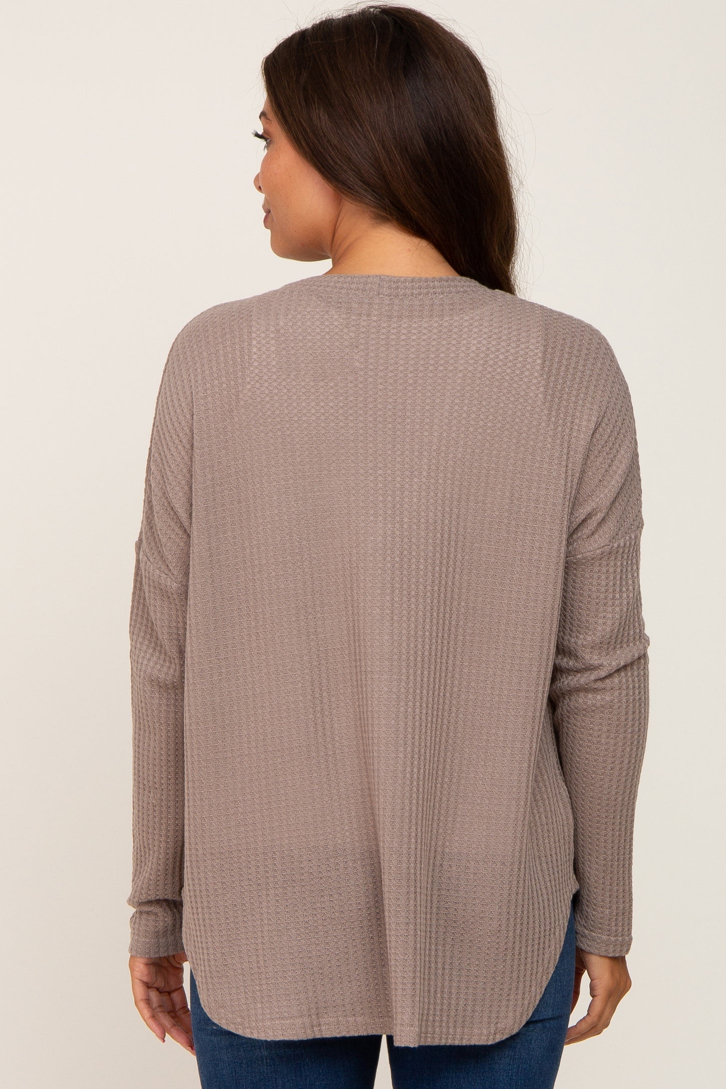 woman wearing a taupe long sleeve maternity top with a relaxed fit and back yoke detail
