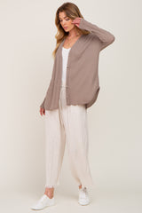 woman wearing a beige ribbed cardigan over a white tank top and light linen pants, styled with white sneakers