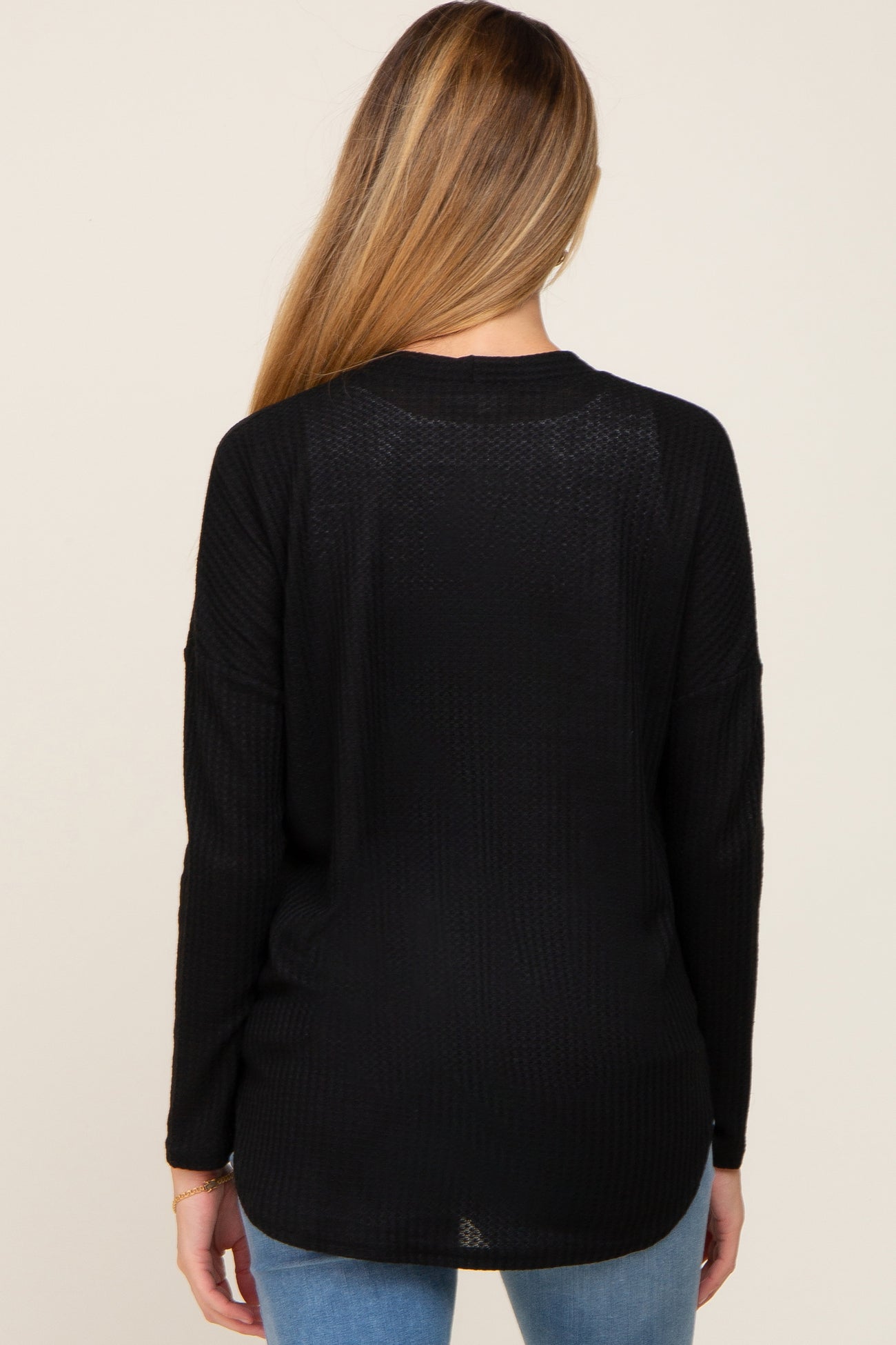 black long sleeve maternity top with a relaxed fit, viewed from the back, styled with blue jeans