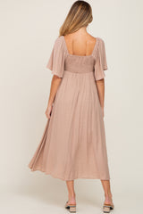 woman wearing a mauve maternity dress with flutter sleeves and a smocked back