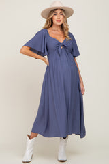 woman wearing a navy blue maternity dress with short flutter sleeves and a front knot, highlighting her baby bump