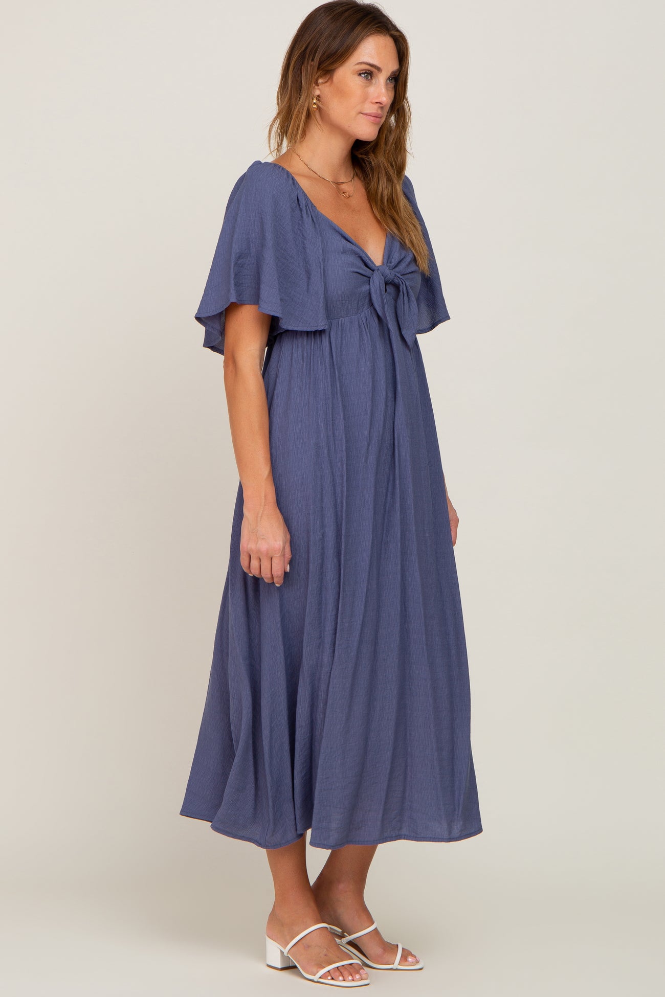 woman wearing a navy blue maxi dress with a tie front and flutter sleeves