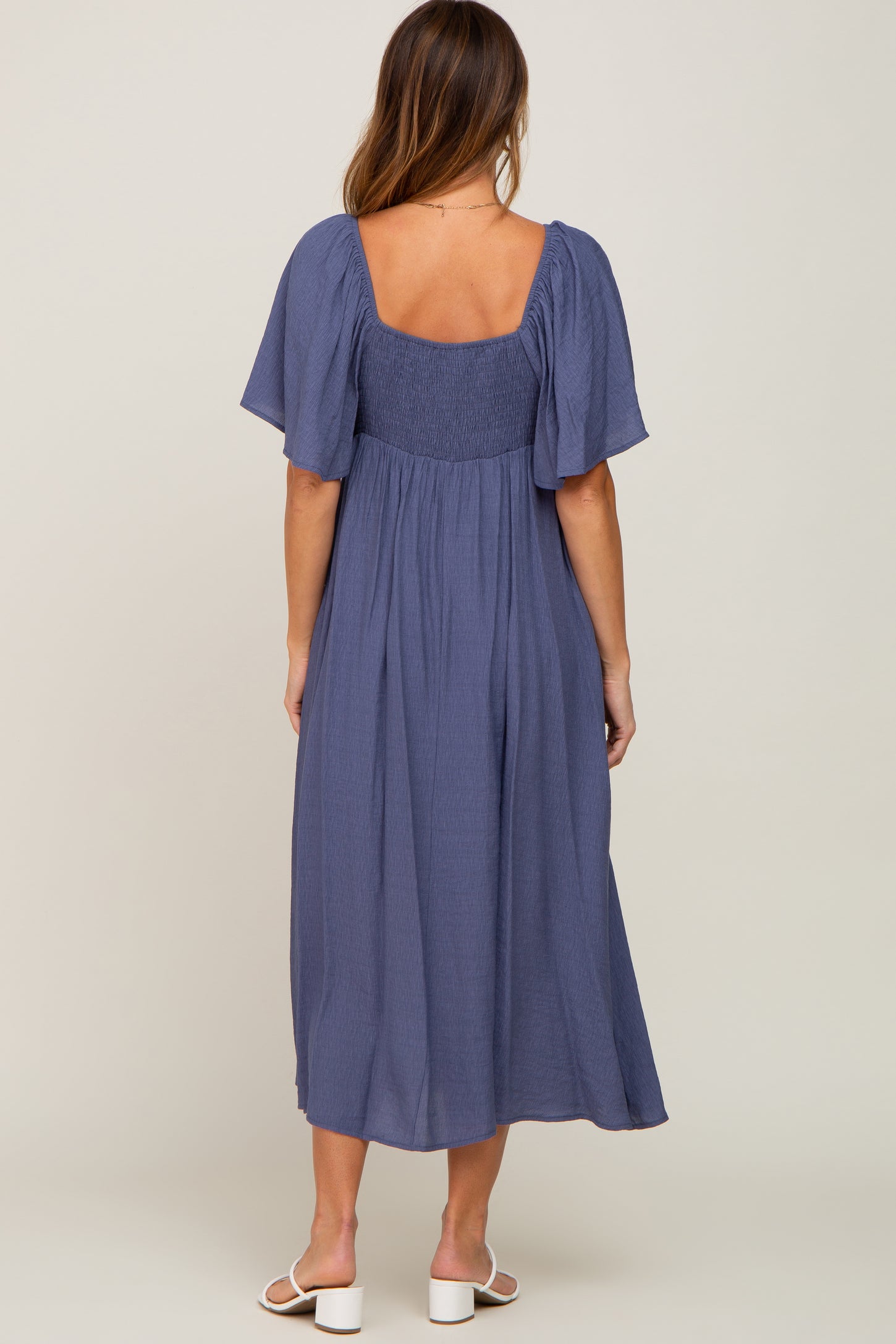woman wearing a navy blue midi dress with short puff sleeves and a smocked bodice from the back
