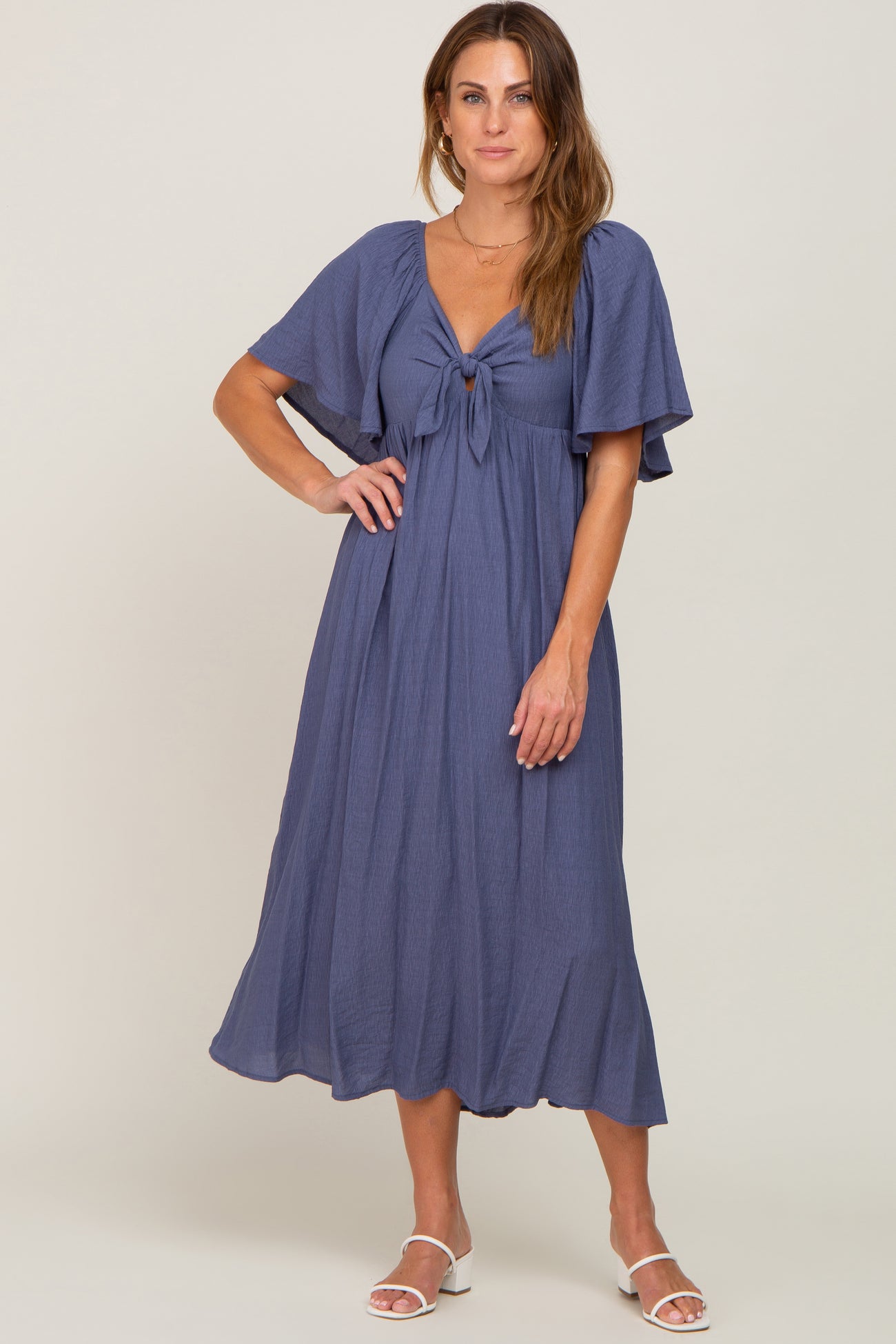 woman wearing a navy blue midi dress with a front tie detail and flutter sleeves