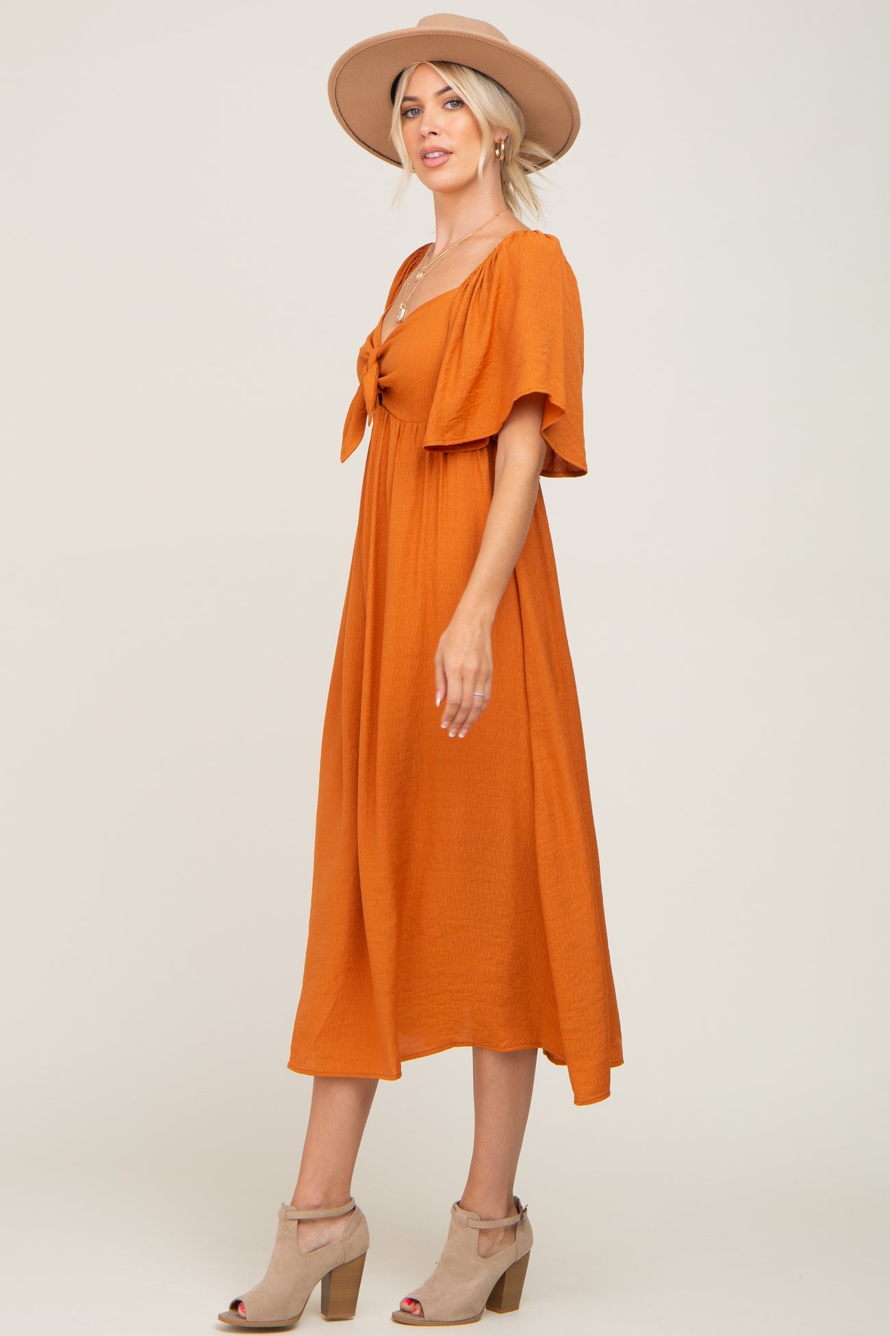 woman wearing an orange short sleeve midi dress with a tie front and a wide-brimmed hat