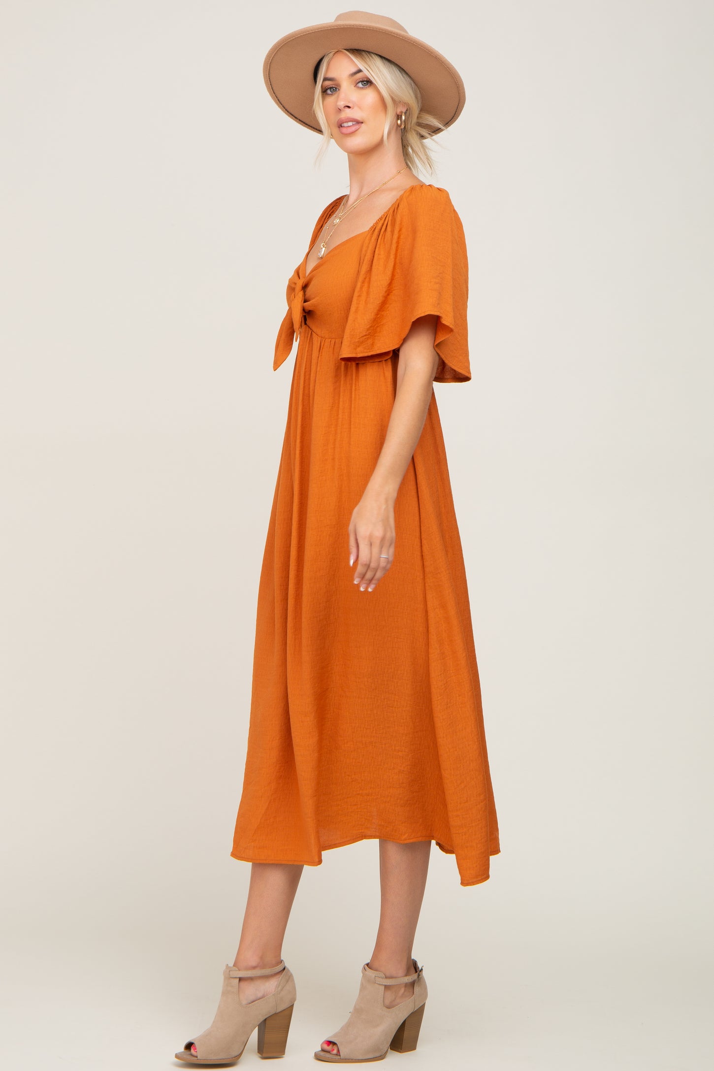 woman wearing an orange short sleeve midi dress with a tie front and a wide-brimmed hat