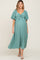 woman wearing a teal maternity maxi dress with a tie front and flutter sleeves, showing her baby bump