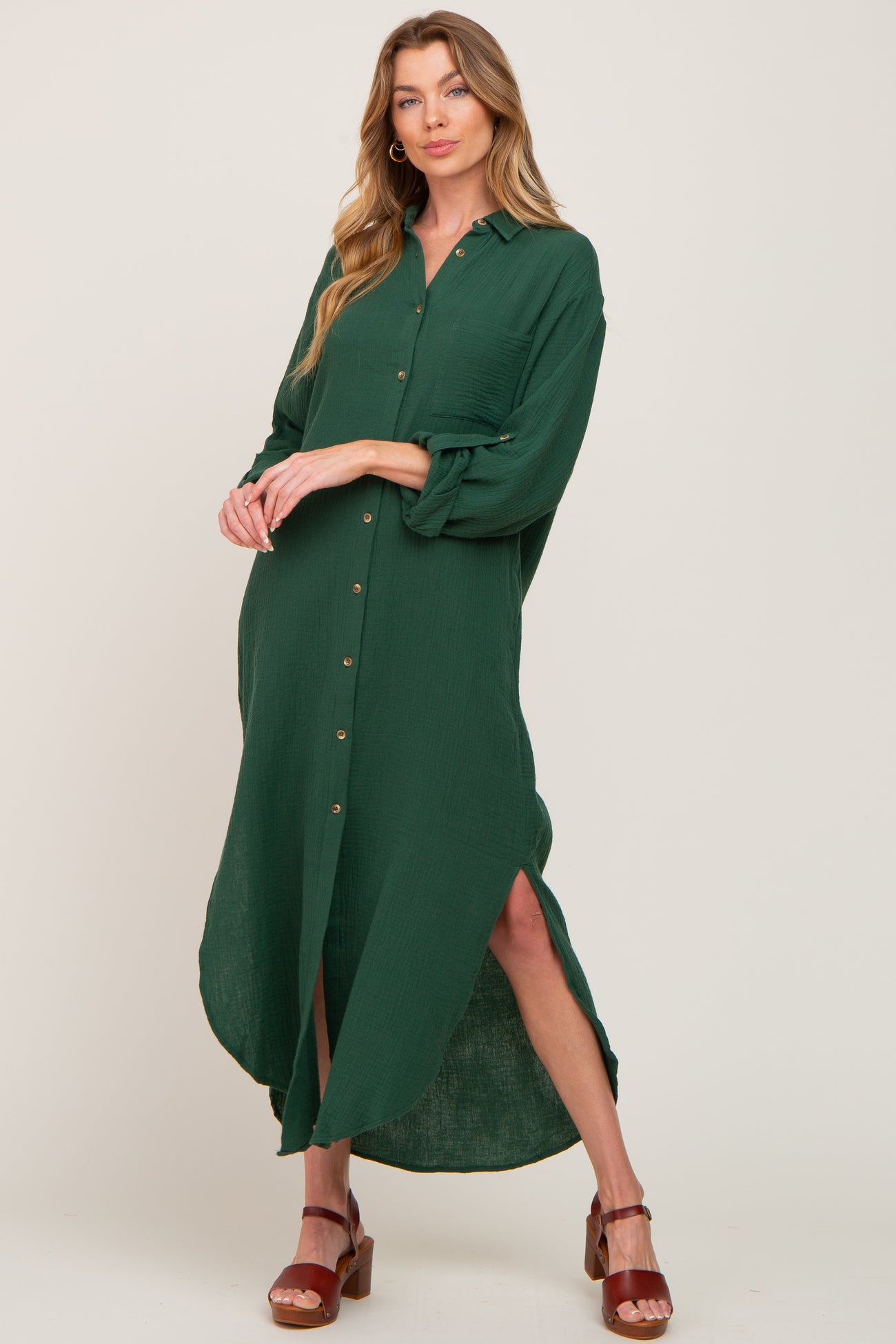 woman wearing a long sleeve forest green button down maxi shirt dress with side slits and brown heels