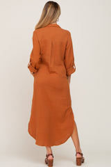 back view of woman wearing rust orange long sleeve gauze shirt dress with high low hem and brown sandals