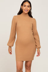 woman wearing a camel ribbed maternity sweater dress with long puff sleeves and a visible baby bump