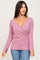 woman wearing a light pink long sleeve wrap top with side slits and a v-neckline, paired with blue jeans