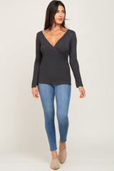 woman wearing a charcoal grey long sleeve surplice top and blue skinny jeans with tan mules
