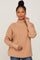 woman wearing a beige turtleneck sweater with ribbed texture and button details on the sleeves