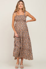woman wearing a brown floral maternity maxi dress with adjustable straps and a visible baby bump