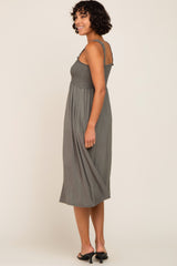 woman wearing a gray smocked midi dress with a flowy skirt and spaghetti straps, shown from the side