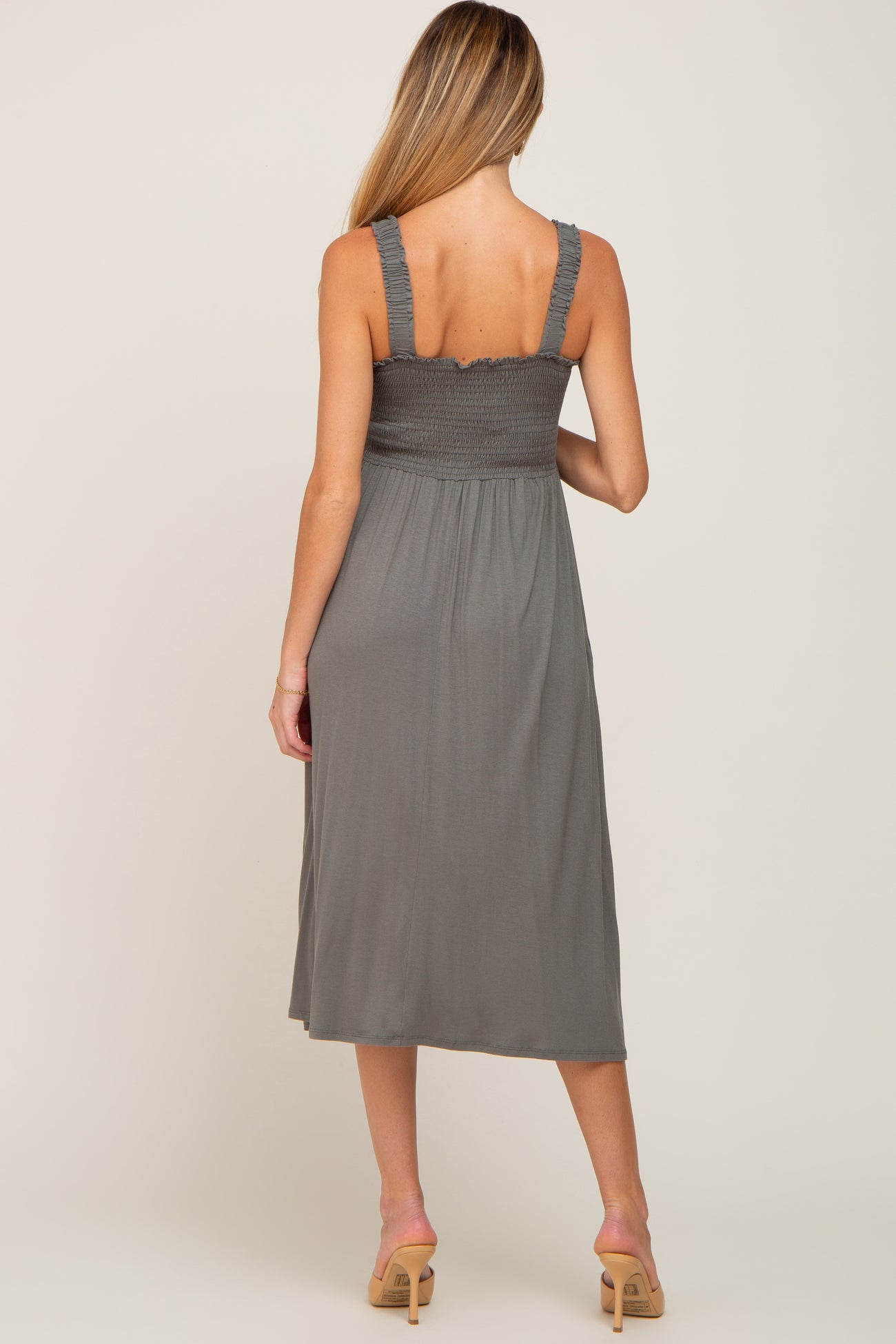 woman wearing a gray smocked maternity dress with spaghetti straps and a midi length, showing a stylish back view