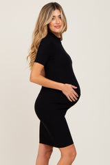 pregnant woman in a black short sleeve maternity bodycon dress holding her belly
