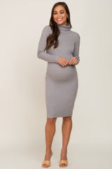 Smiling pregnant woman wearing a grey ribbed turtleneck maternity midi dress and tan heels