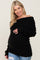 smiling pregnant woman wearing a black off-the-shoulder maternity sweater and distressed jeans