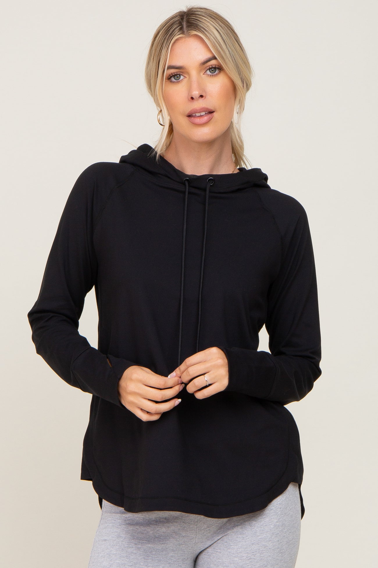 woman wearing a black long sleeve hooded top with drawstrings and grey leggings