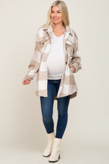 pregnant woman wearing tan plaid maternity shacket with white top and blue jeans