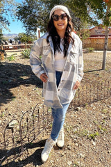 Woman in grey plaid shacket, beanie, and sunglasses standing outdoors at a farm in autumn fashion