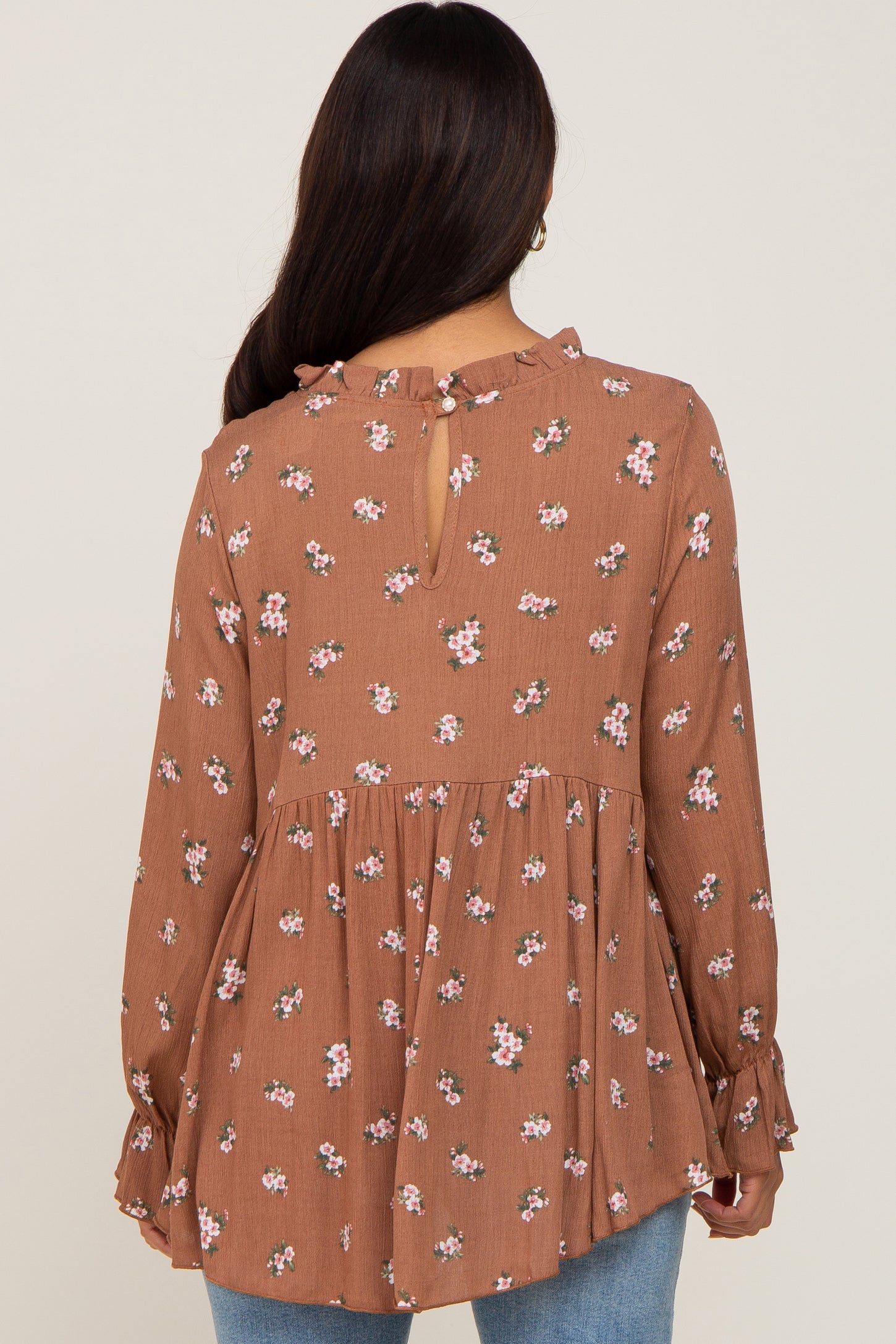 woman wearing a brown floral maternity blouse with long sleeves and ruffle details, showing a keyhole back设计