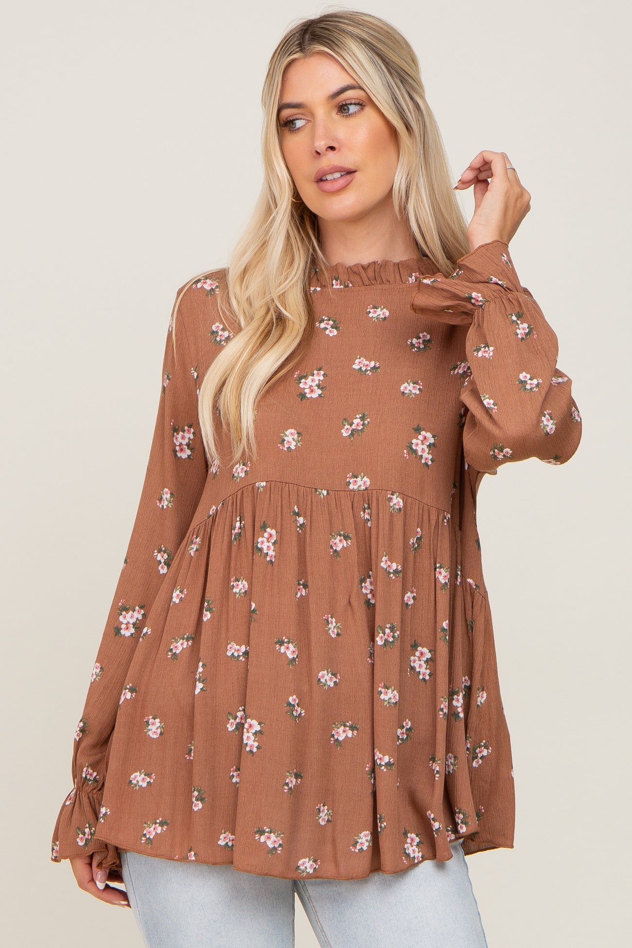 woman wearing a brown floral print long sleeve top with a ruffled neckline and a flowy silhouette