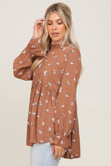 woman wearing a brown floral long sleeve top with a ruffled neckline and peplum hem, styled with light wash jeans