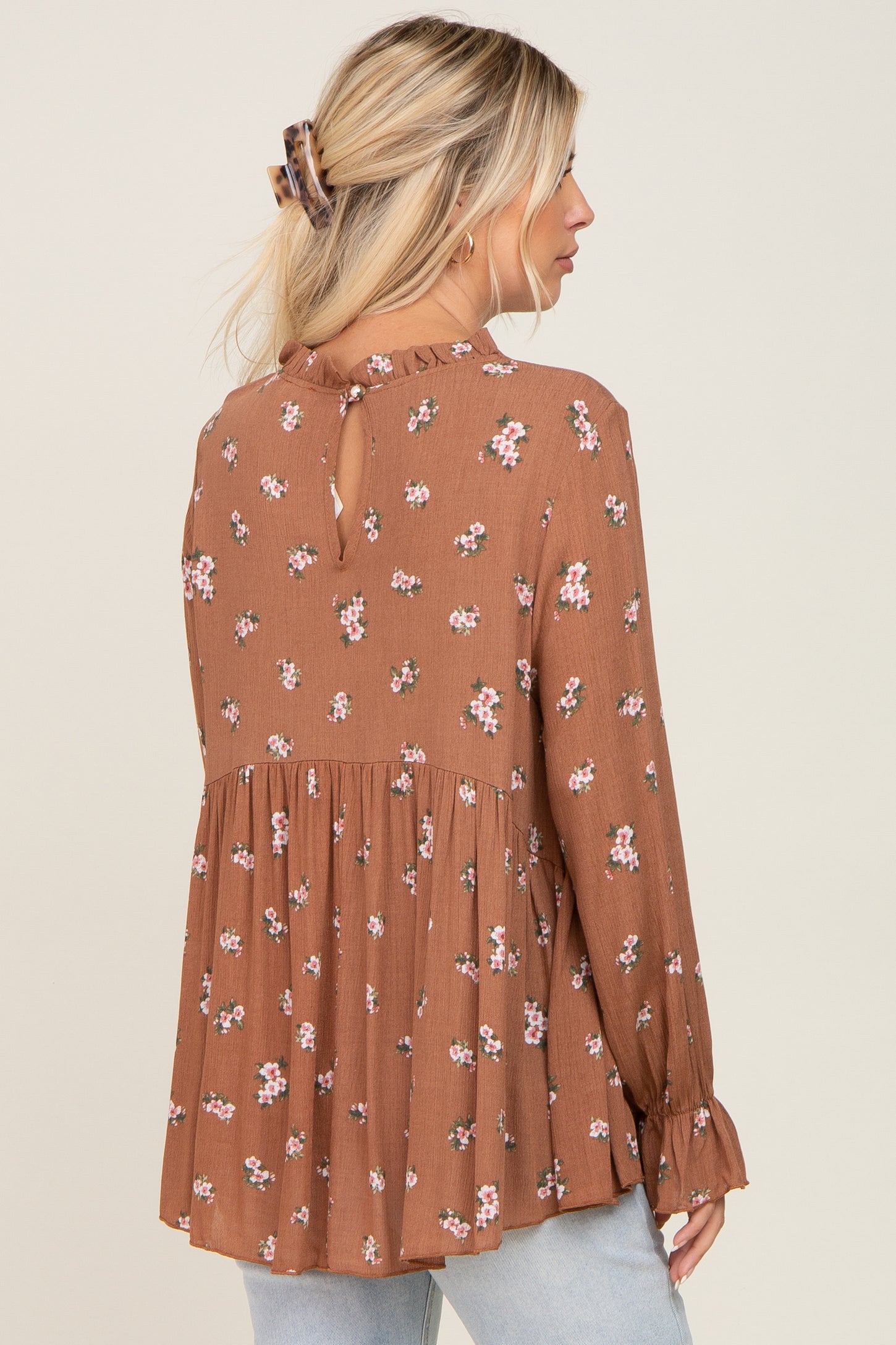 woman wearing a brown floral long sleeve blouse with a pleated peplum and keyhole back detail