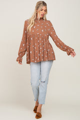 woman wearing a brown floral long sleeve peplum top paired with light blue distressed jeans and brown slip-on shoes