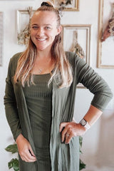 woman wearing an olive green ribbed dress layered with a matching long cardigan and smiling at the camera