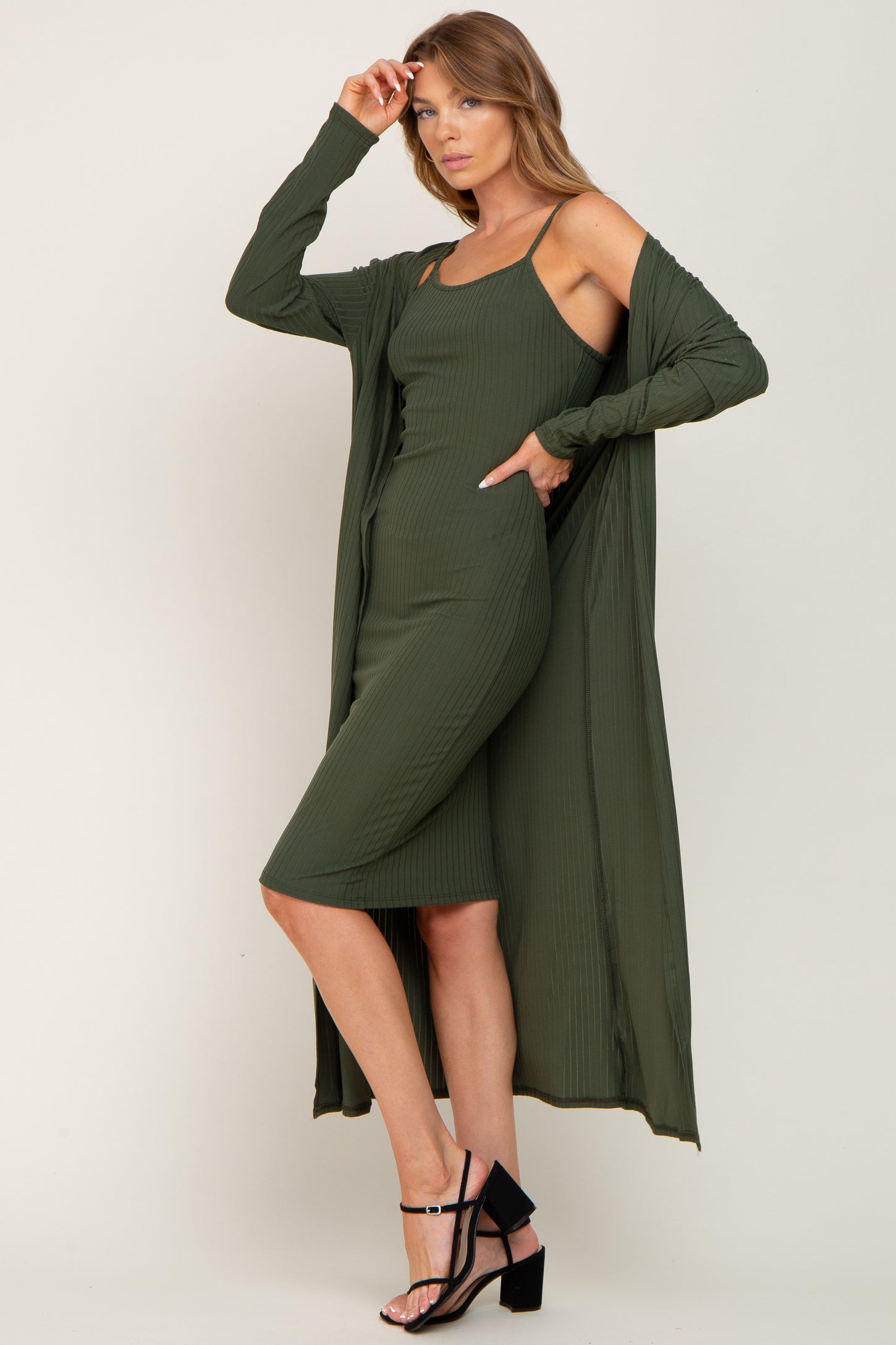 woman wearing a dark green ribbed midi dress with a matching long cardigan and strappy black heels