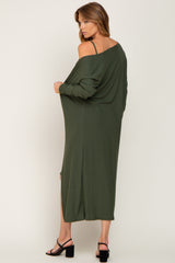 woman wearing a long olive green off-shoulder dress with side slits and a relaxed fit, standing with her back to the camera