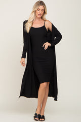 woman wearing a black ribbed tank dress with a long black cardigan over it and black slide sandals