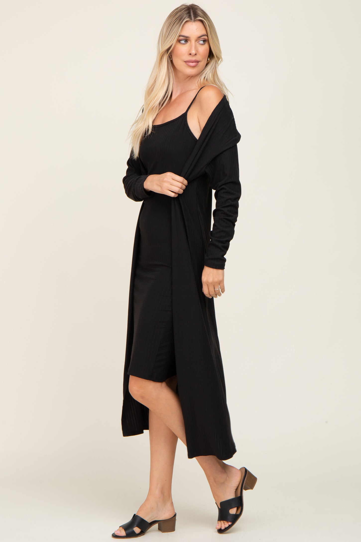 woman wearing a black ribbed midi dress with a coordinating black long cardigan and black heeled sandals