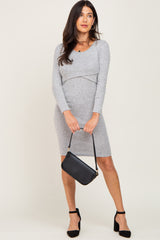 woman wearing a grey long sleeve fitted dress and holding a black handbag