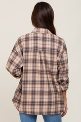 Back view of a woman wearing an oversized tan and blue plaid flannel shirt with blue jeans